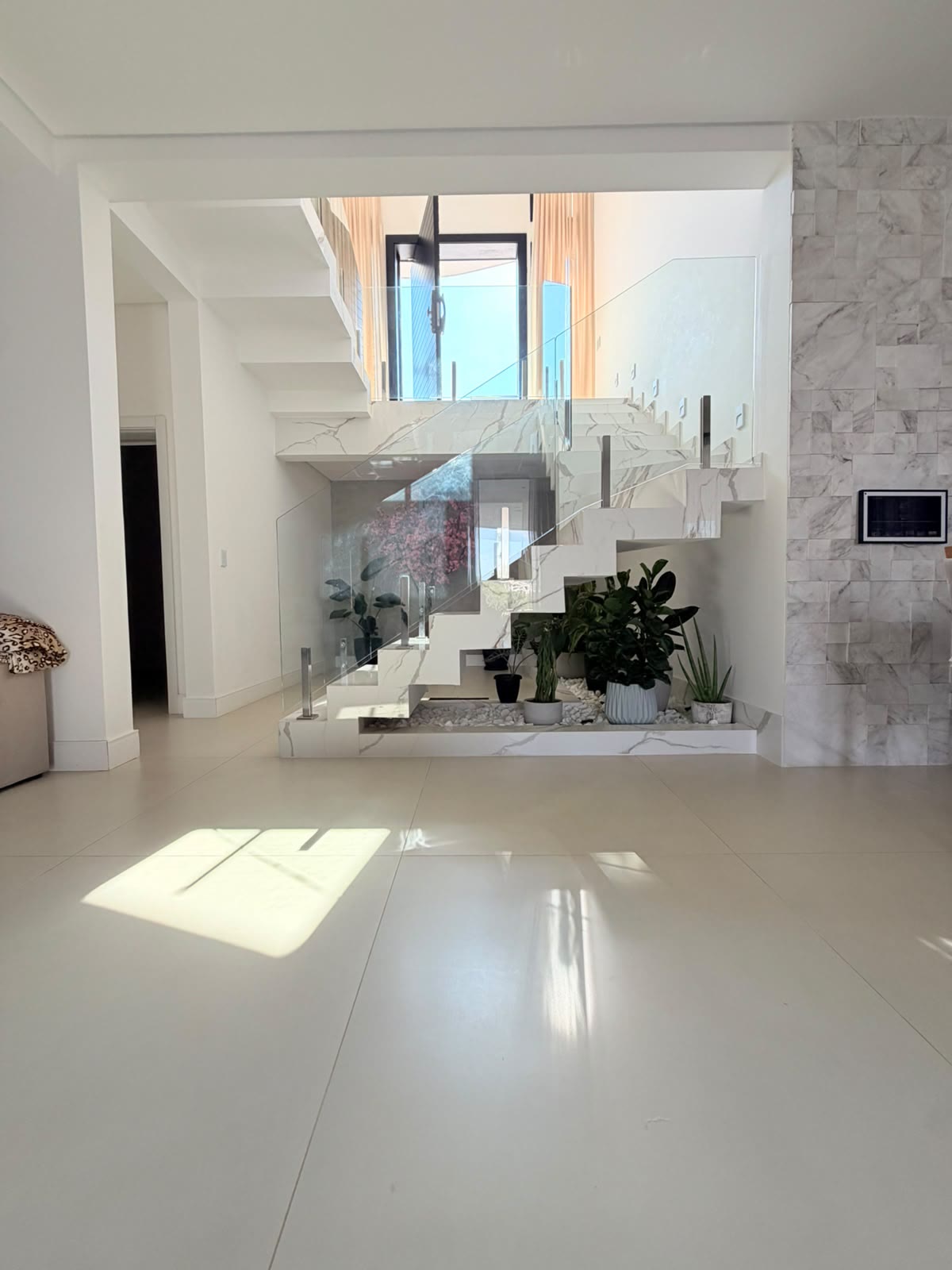Hall com escada em mármore claro e jardim interno