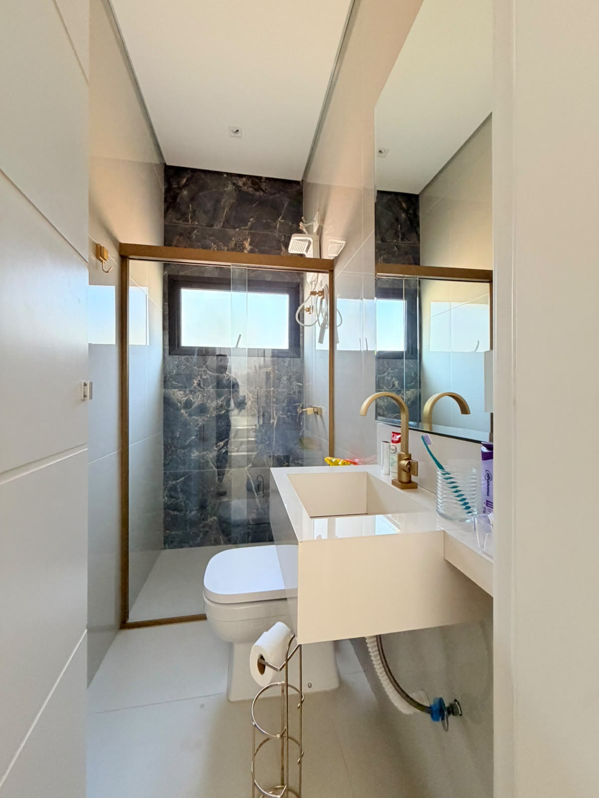 Lavabo com revestimento em pedra escura e metais dourados